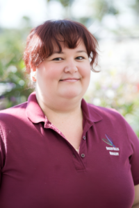 Demaree Holland, Accounting representative at Green Hills Nursery, wearing a maroon polo shirt with the Green Hills Nursery logo."